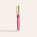 Pink sheer silk lip oil in a clear tube with a gold decorative cap standing upright